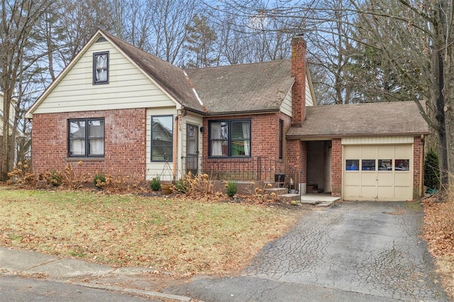 view of front of home featuring brick siding, a shingled roof, a chimney, driveway, and an attached garage