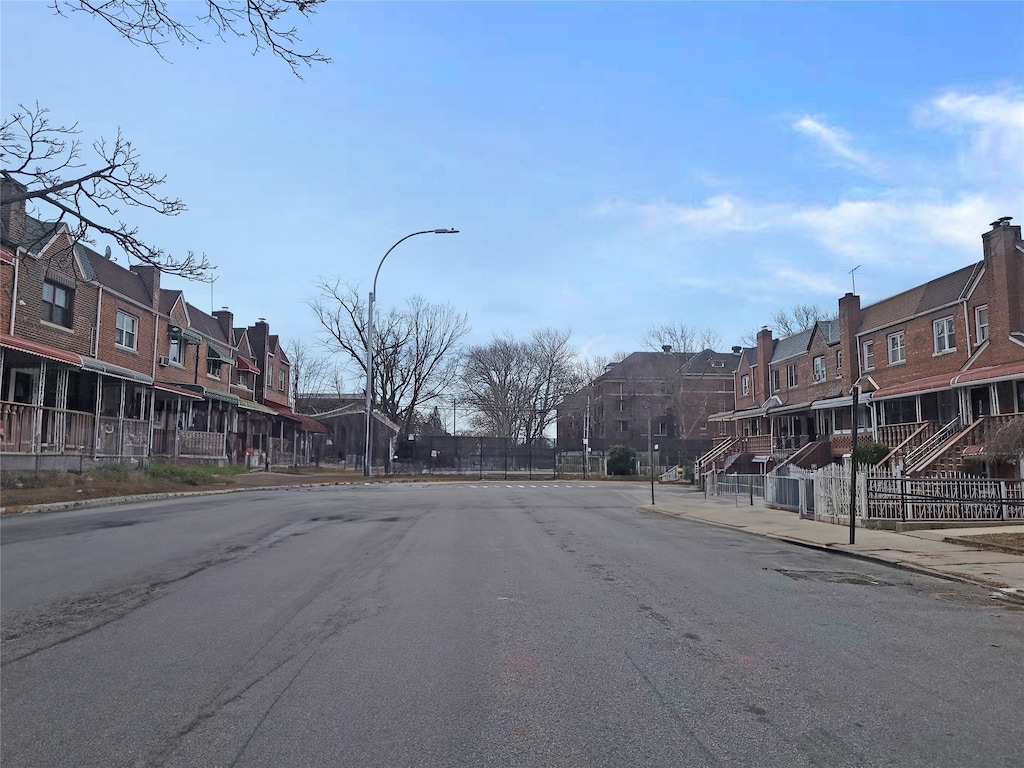 view of street featuring street lights, curbs, sidewalks, and a residential view