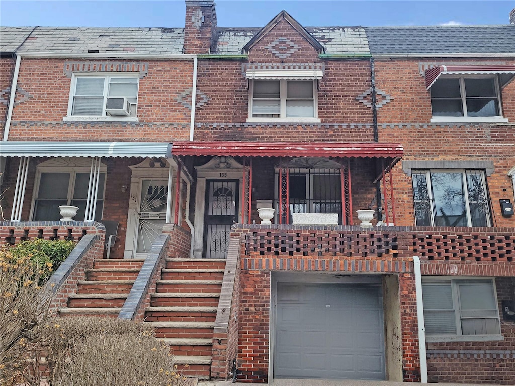 view of property with mansard roof, an attached garage, cooling unit, a high end roof, and brick siding