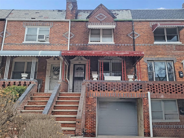 view of property with mansard roof, an attached garage, cooling unit, a high end roof, and brick siding