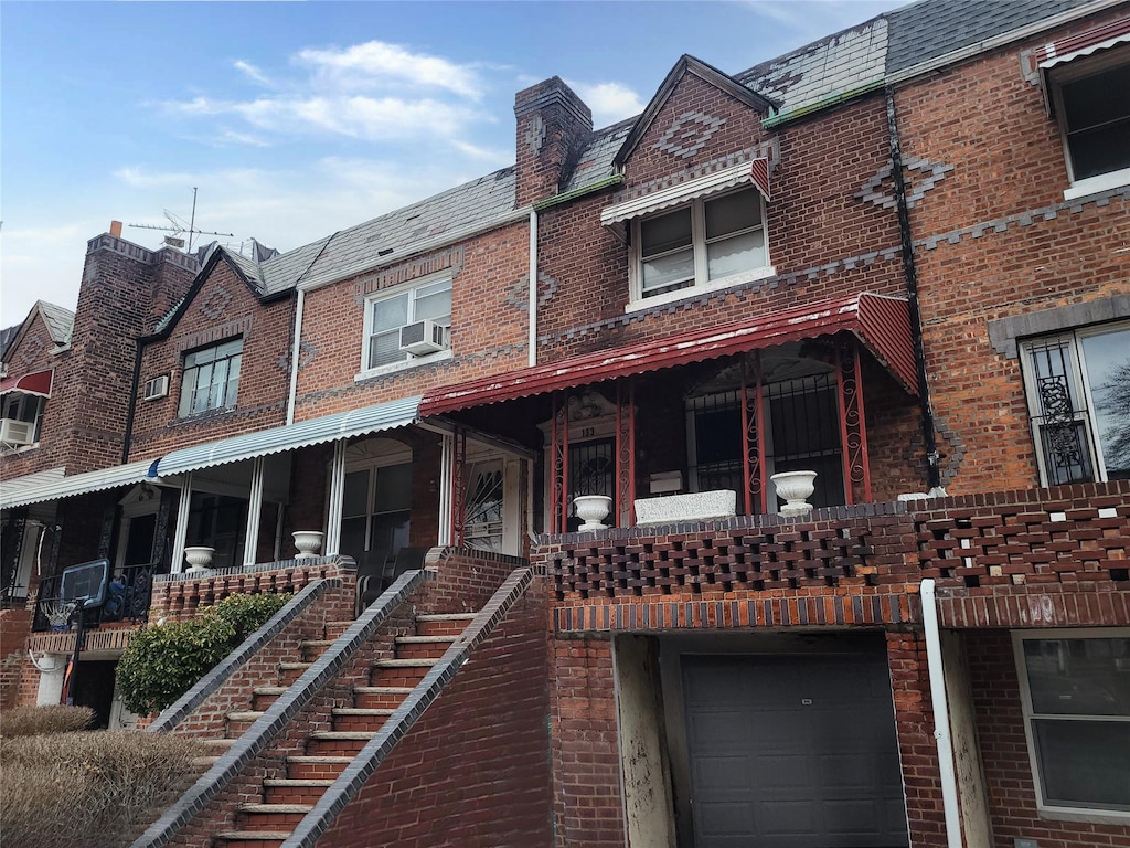 view of front of house featuring a garage, a high end roof, brick siding, and mansard roof