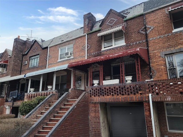 view of front of house featuring a garage, a high end roof, brick siding, and mansard roof