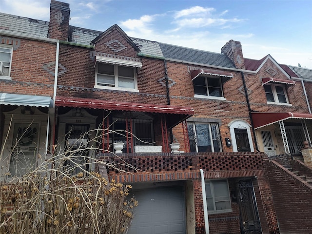 back of property featuring brick siding, mansard roof, and a high end roof