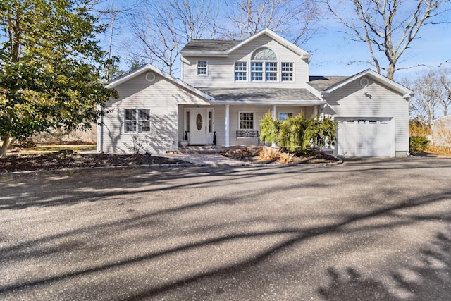 traditional-style home featuring aphalt driveway, an attached garage, and a shingled roof