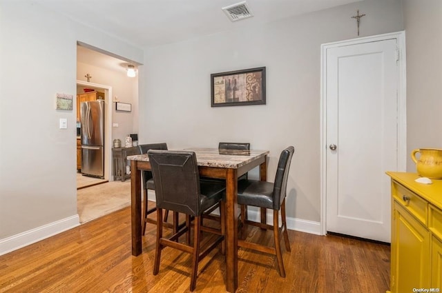 dining room featuring wood finished floors, visible vents, and baseboards