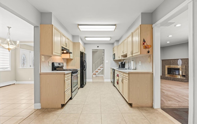 kitchen featuring stainless steel appliances, light brown cabinets, light countertops, and under cabinet range hood