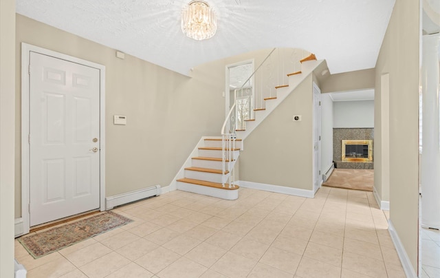 entryway with a baseboard heating unit, stairway, a glass covered fireplace, and baseboards