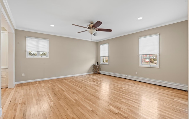 spare room featuring ornamental molding, light wood-type flooring, a wealth of natural light, and baseboards