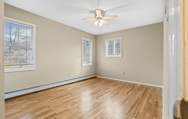 empty room featuring a baseboard heating unit, a wealth of natural light, ceiling fan, and light wood-style flooring