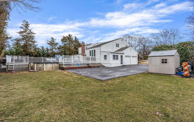 back of property with an outbuilding, driveway, a yard, a wooden deck, and a storage unit