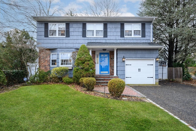 traditional home featuring brick siding, an attached garage, fence, driveway, and a front lawn