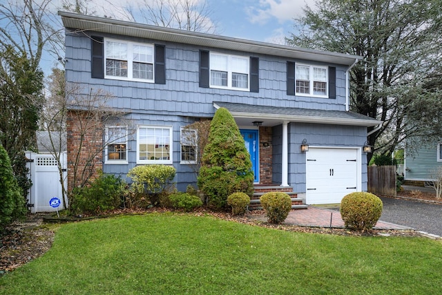 traditional-style home featuring aphalt driveway, a garage, fence, and a front lawn