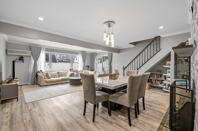 dining space featuring light wood-style floors, ornamental molding, and stairs