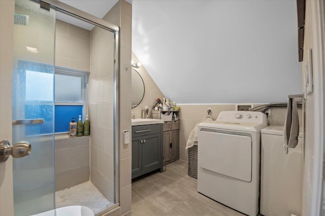 interior space featuring visible vents, light wood-type flooring, washer and clothes dryer, tile walls, and laundry area