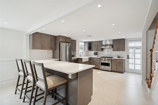 kitchen featuring tasteful backsplash, appliances with stainless steel finishes, wall chimney exhaust hood, and a peninsula