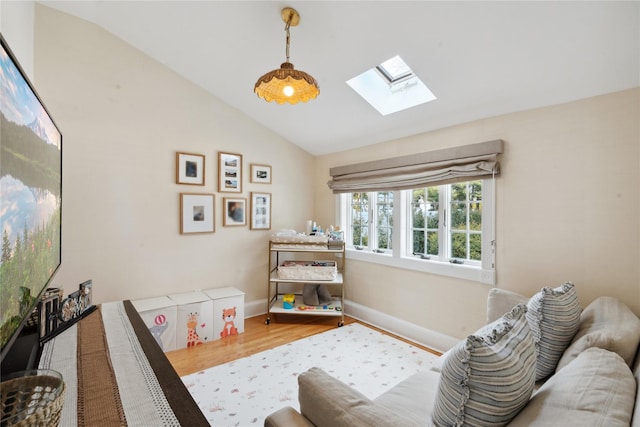 bedroom with vaulted ceiling with skylight, wood finished floors, and baseboards