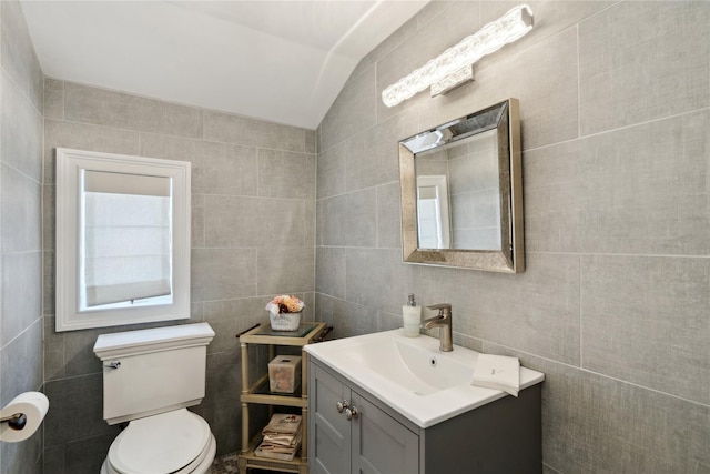 bathroom featuring vanity, tile walls, toilet, and vaulted ceiling