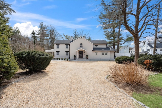 traditional-style home with gravel driveway and stucco siding