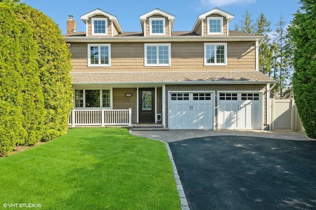 view of front of home with a porch, driveway, roof with shingles, a front yard, and a garage
