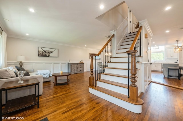 stairway featuring ornamental molding, a decorative wall, recessed lighting, and wood finished floors