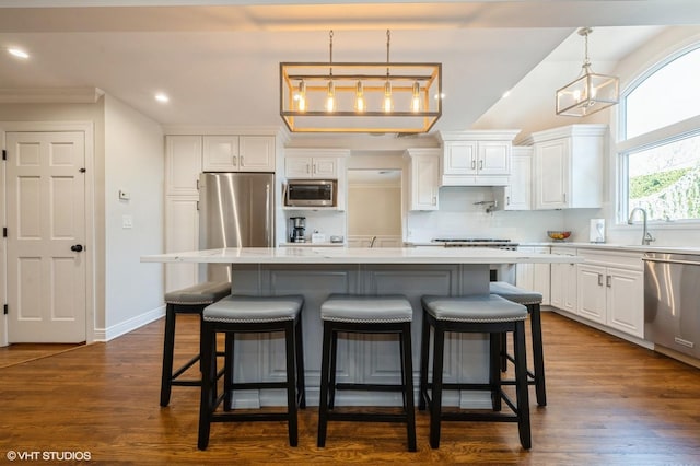 kitchen with appliances with stainless steel finishes, white cabinets, backsplash, and a kitchen island