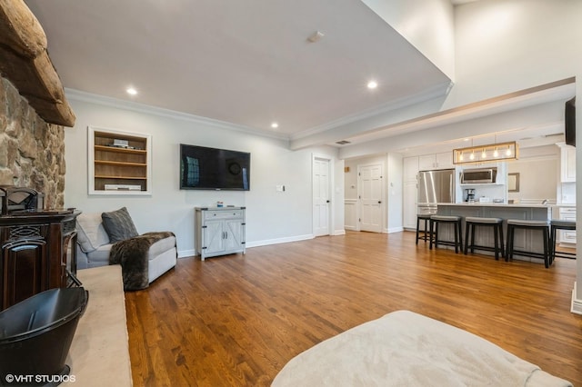 living room featuring baseboards, ornamental molding, recessed lighting, and wood finished floors
