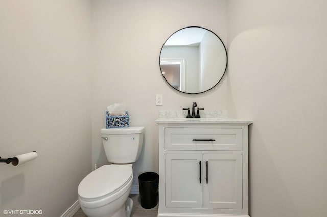 bathroom with vanity, baseboards, and toilet