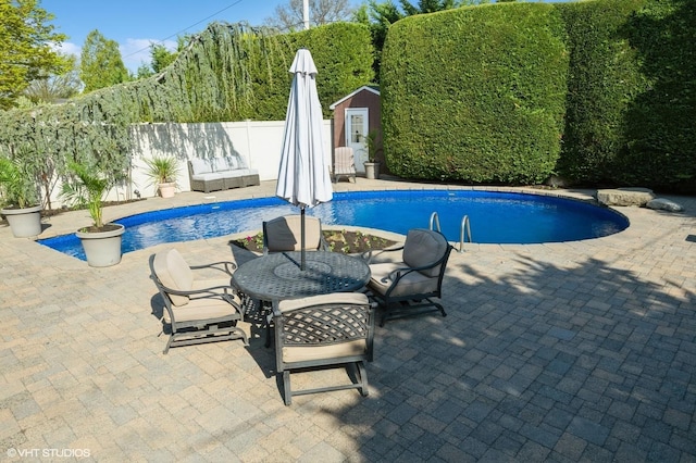 view of swimming pool featuring fence, an outbuilding, a patio area, and a shed