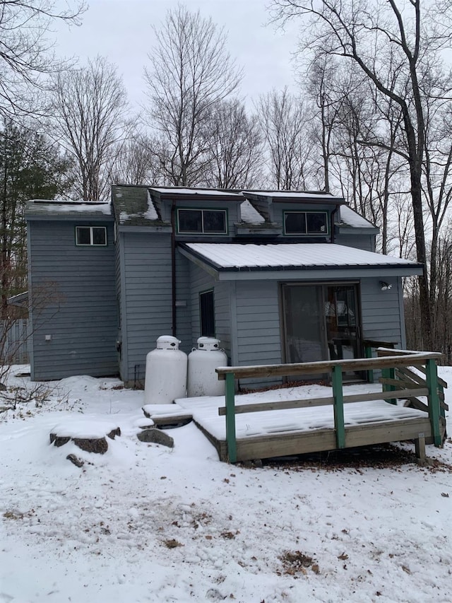 snow covered property with a garage and a deck