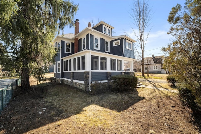 back of property featuring fence, a sunroom, and a chimney