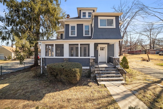 view of front of house with covered porch, a chimney, and a sunroom