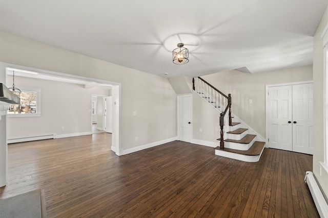 unfurnished living room with a baseboard heating unit, baseboards, hardwood / wood-style flooring, and stairway