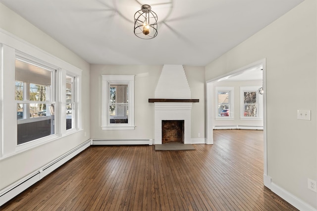 unfurnished living room featuring a baseboard heating unit, dark wood-type flooring, baseboard heating, and a large fireplace