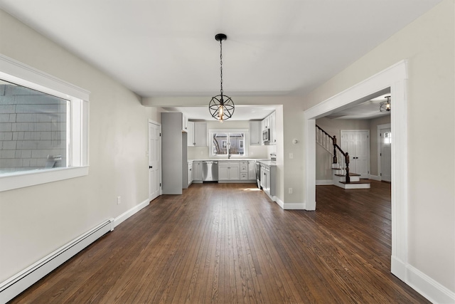 unfurnished dining area featuring dark wood-type flooring, stairway, baseboards, and baseboard heating