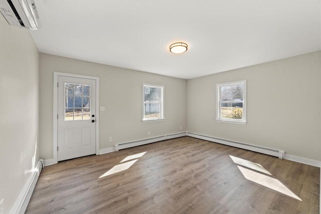 entryway featuring a baseboard heating unit, an AC wall unit, wood finished floors, and baseboards