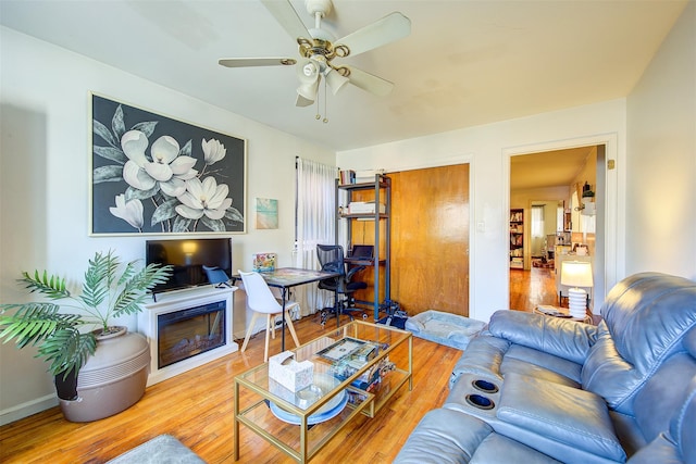 living room featuring a fireplace, ceiling fan, and wood finished floors