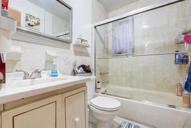 bathroom featuring bath / shower combo with glass door, toilet, vanity, decorative backsplash, and tile walls