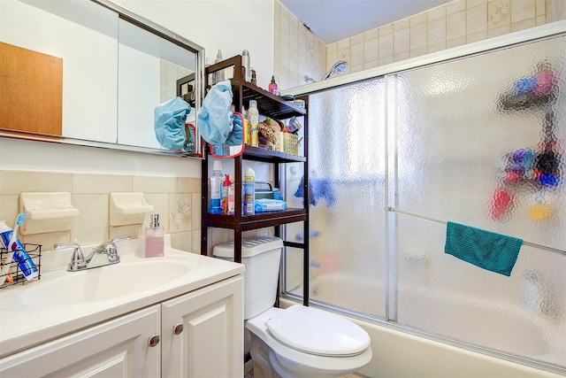 full bath with shower / bath combination with glass door, tile walls, vanity, and toilet