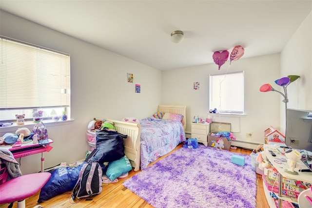 bedroom with multiple windows, a baseboard radiator, a baseboard heating unit, and wood finished floors