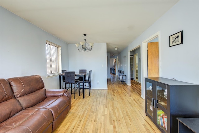 living room featuring baseboards, light wood-type flooring, and a chandelier