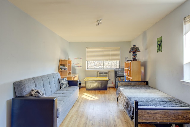 bedroom featuring wood-type flooring, baseboard heating, and a wall mounted AC