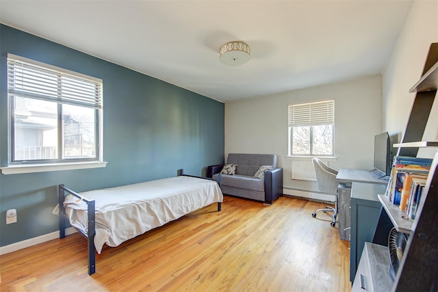 bedroom with light wood-type flooring, baseboards, and a baseboard radiator