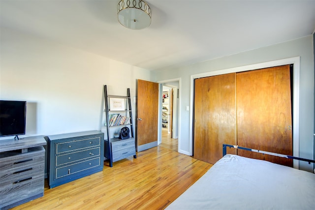 bedroom with a closet, light wood-style flooring, and baseboards