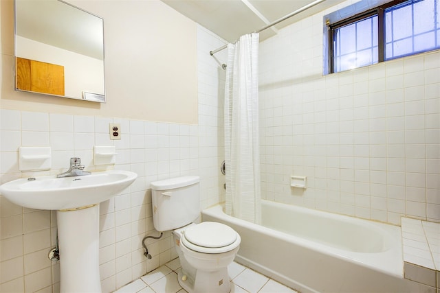 full bathroom featuring tile patterned floors, shower / bathtub combination with curtain, a wainscoted wall, toilet, and tile walls