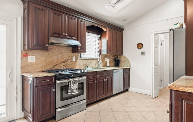 kitchen featuring under cabinet range hood, lofted ceiling with skylight, light tile patterned floors, appliances with stainless steel finishes, and a sink