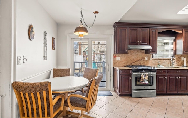 kitchen featuring stainless steel gas stove, under cabinet range hood, a sink, backsplash, and light countertops