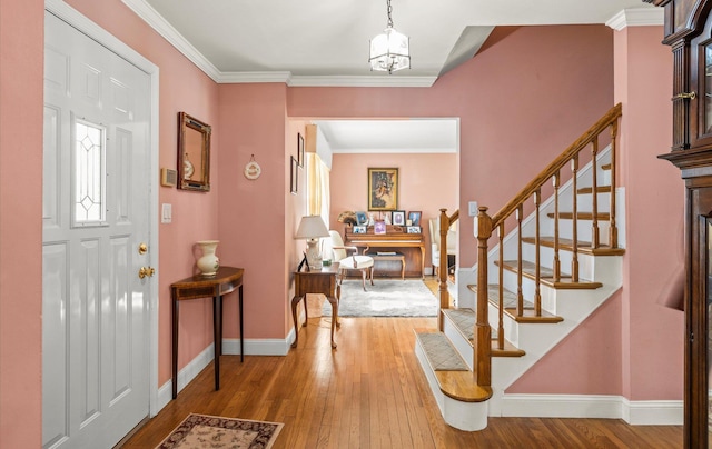 entryway featuring hardwood / wood-style floors, stairway, baseboards, an inviting chandelier, and ornamental molding