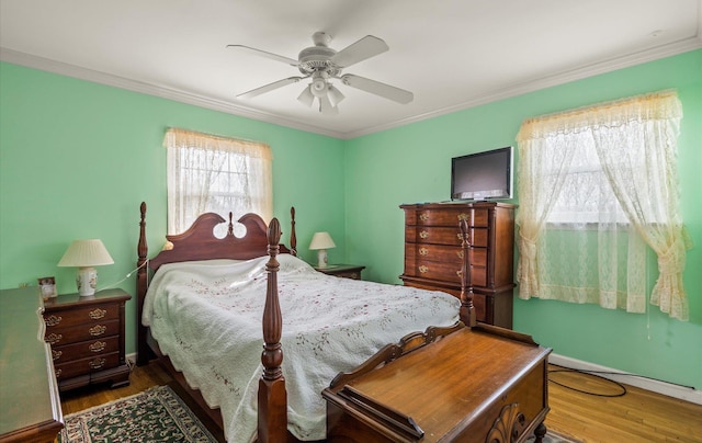 bedroom with baseboards, wood finished floors, a ceiling fan, and ornamental molding