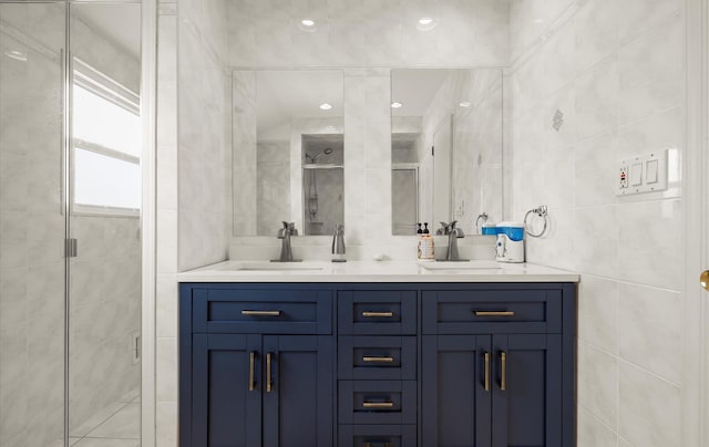 bathroom with a sink, tile walls, a stall shower, and double vanity