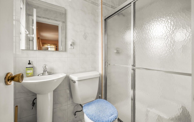 bathroom featuring a shower stall, toilet, and tile walls